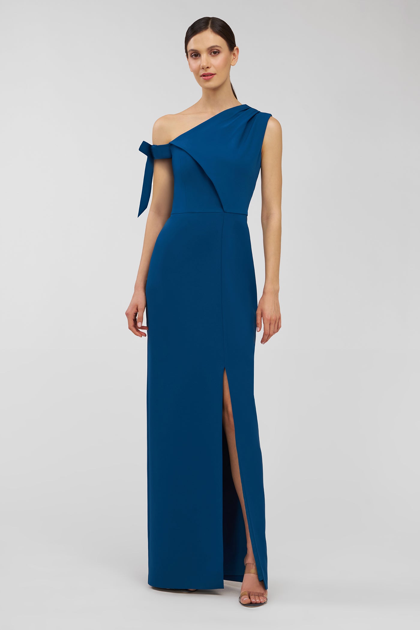 Woman wearing a blue one-shoulder dress with a slit on a white background
