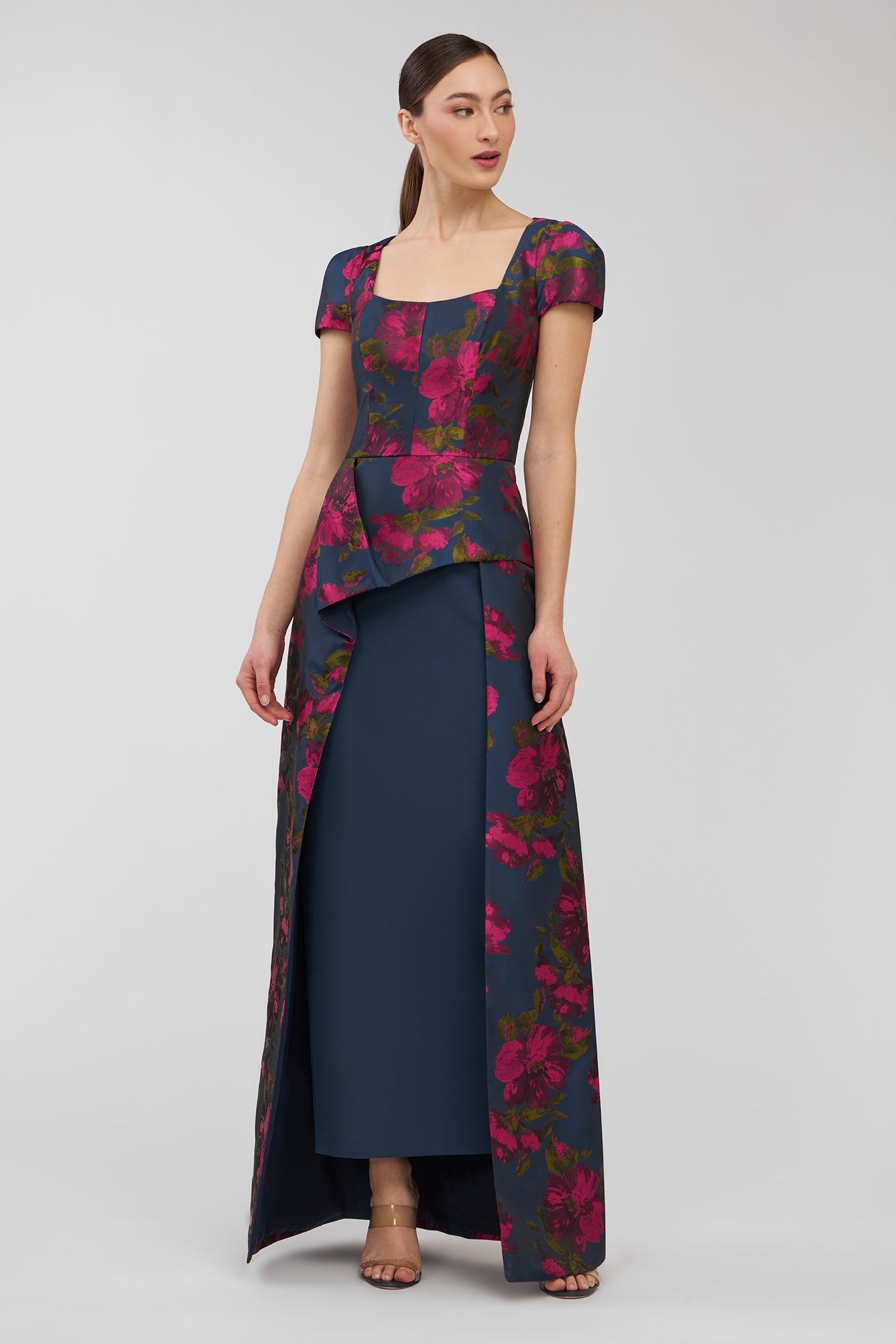 Woman wearing a floral peplum top and long skirt on a white background