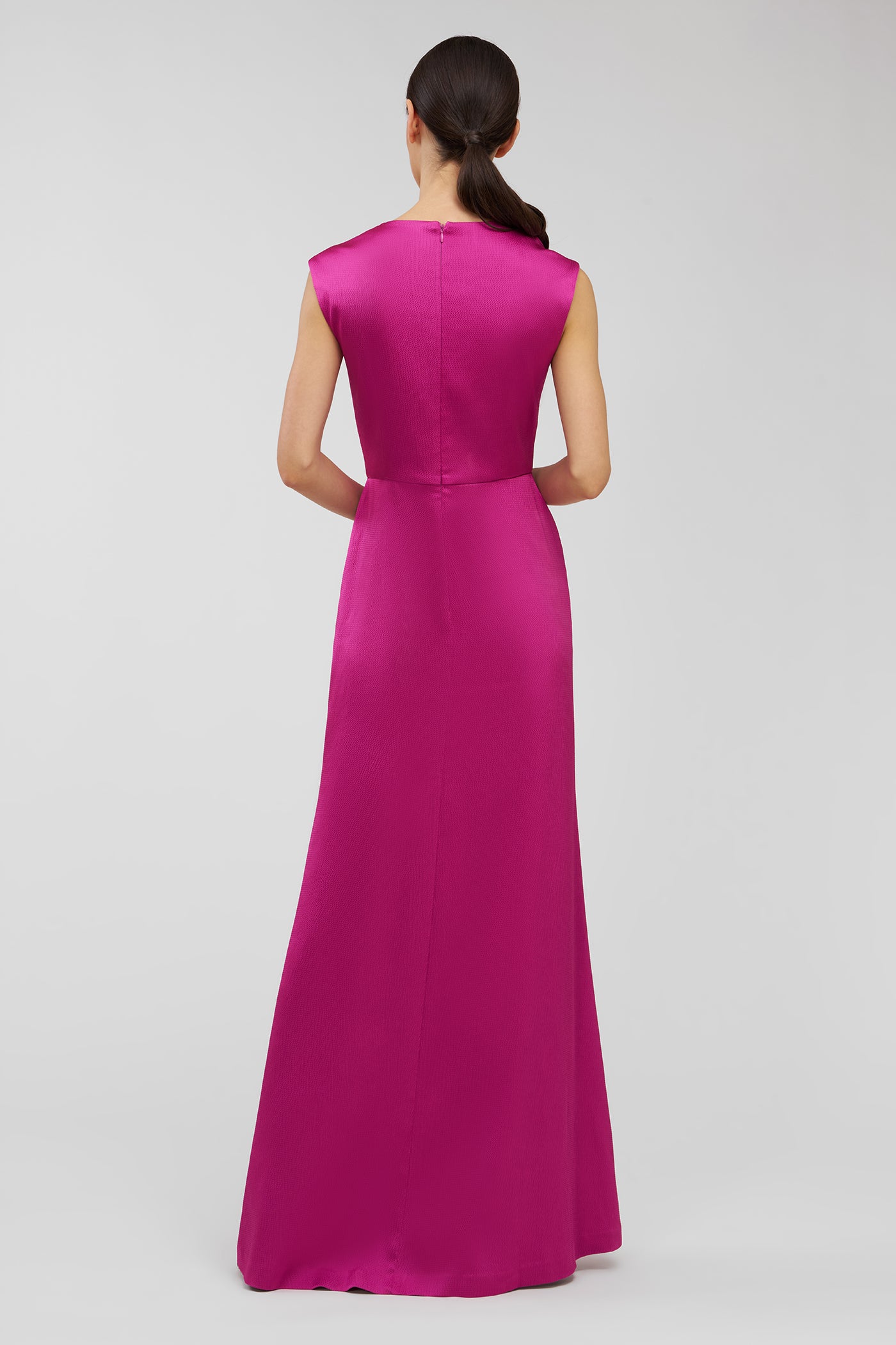 Woman wearing a long pink dress on a light gray background