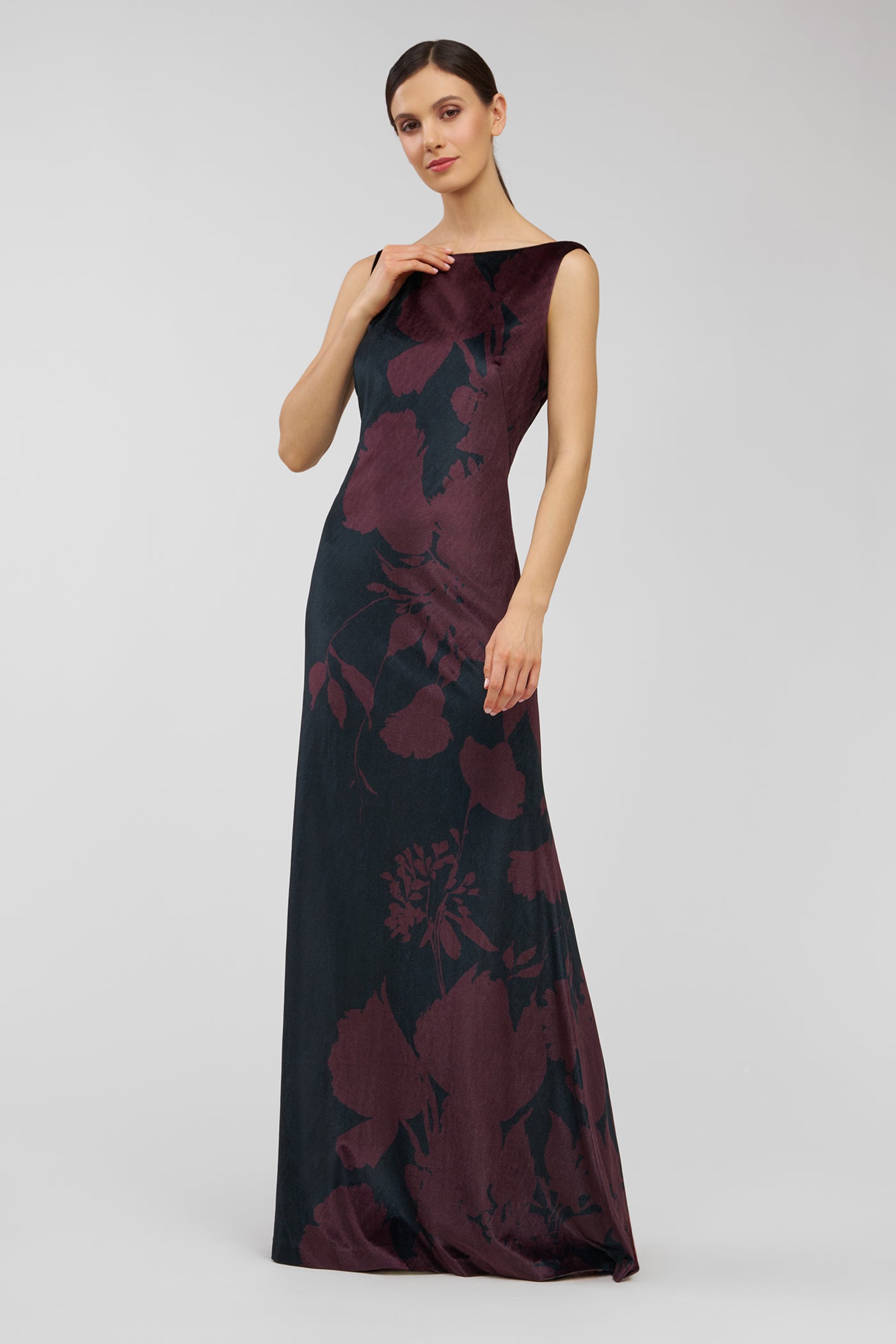 Woman wearing a long, dark floral dress on a light gray background