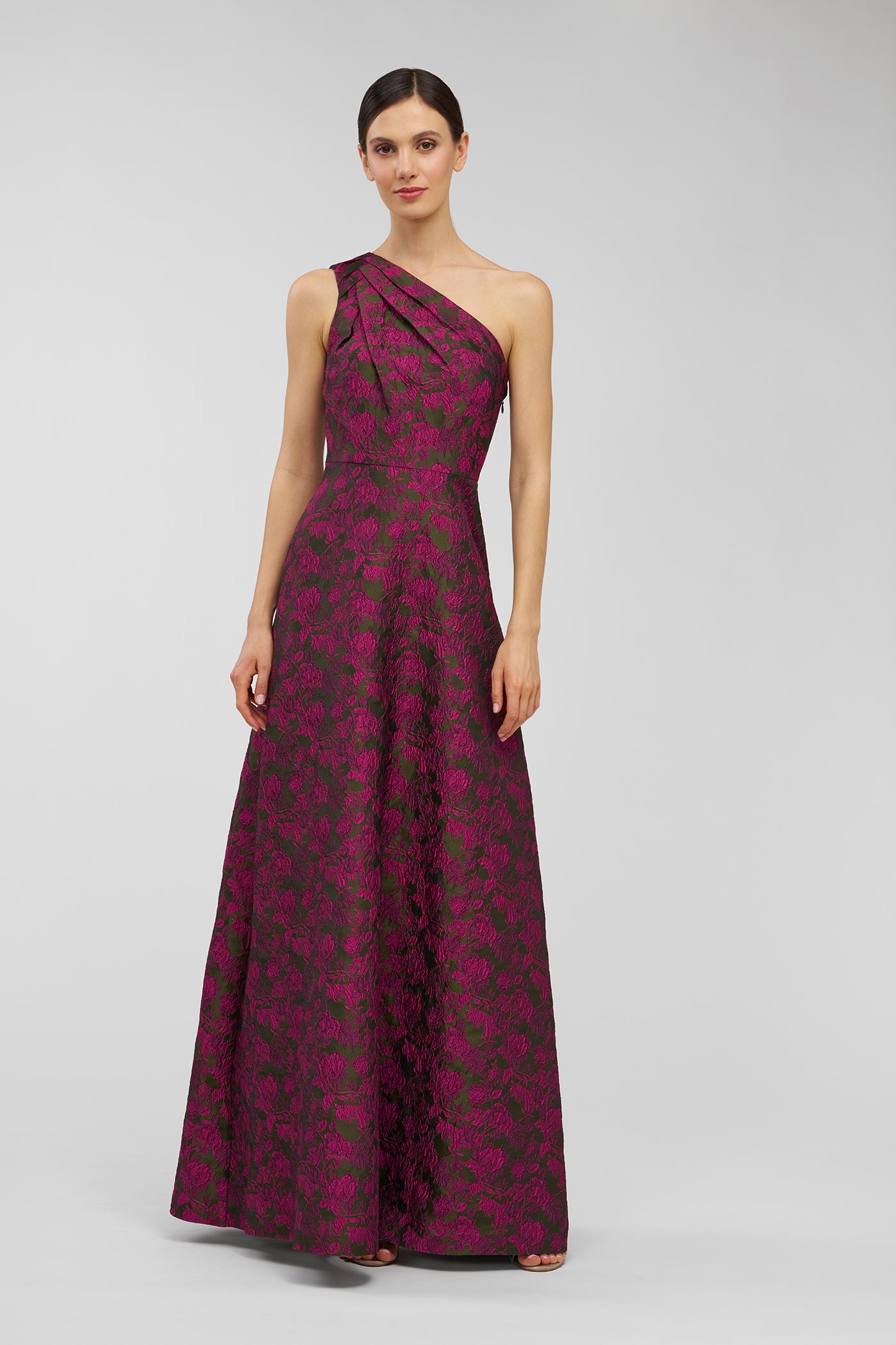Woman wearing a burgundy one-shoulder dress with floral pattern on a light gray background