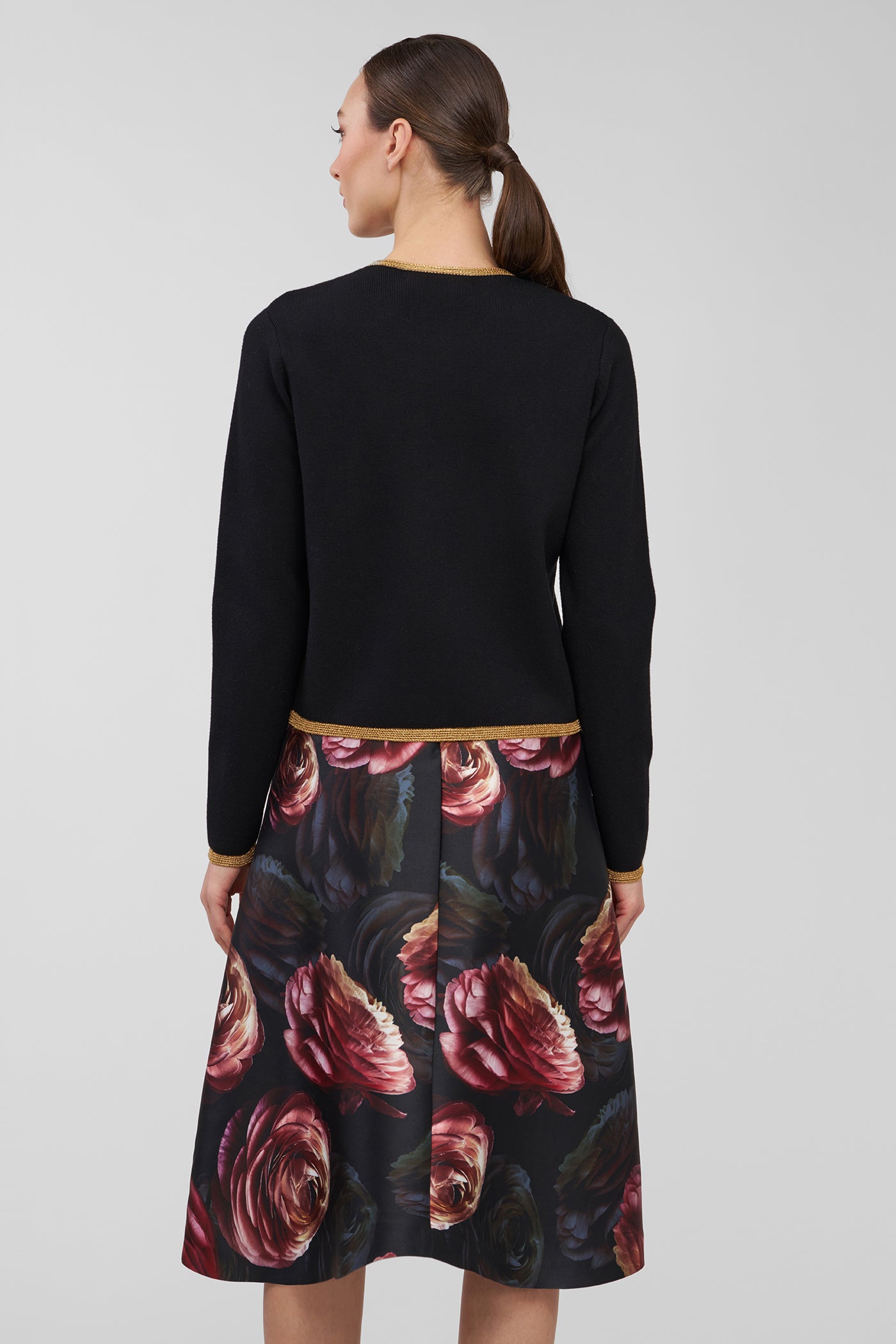 Woman wearing a black long-sleeve cardigan and floral dress on a white background