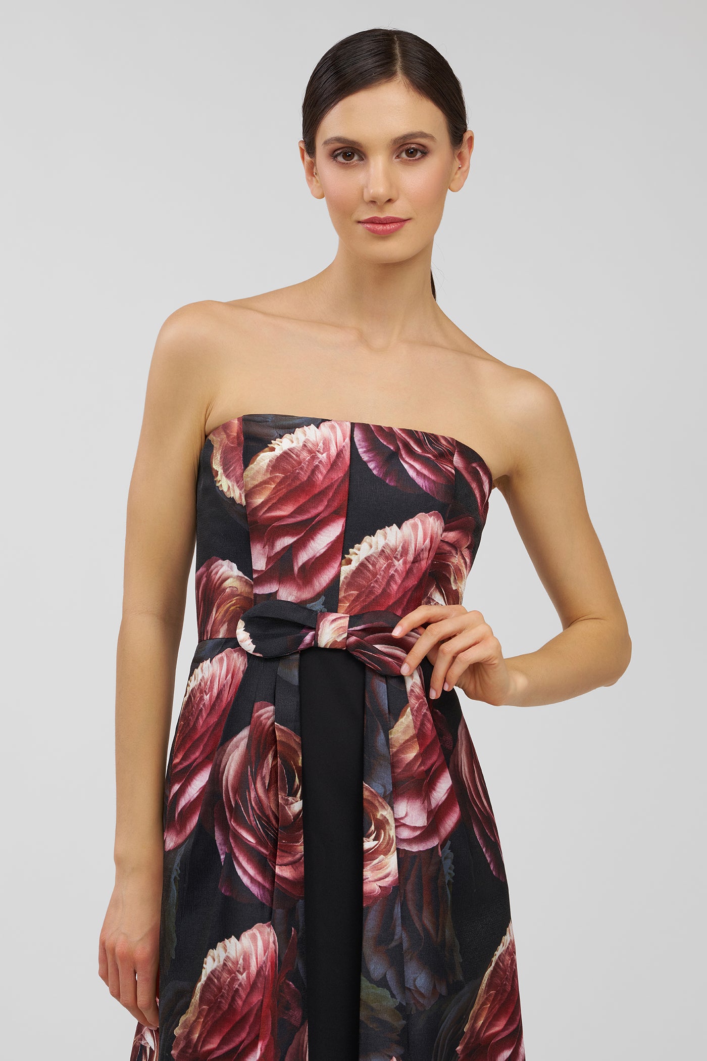 Woman wearing a strapless floral dress on a plain background
