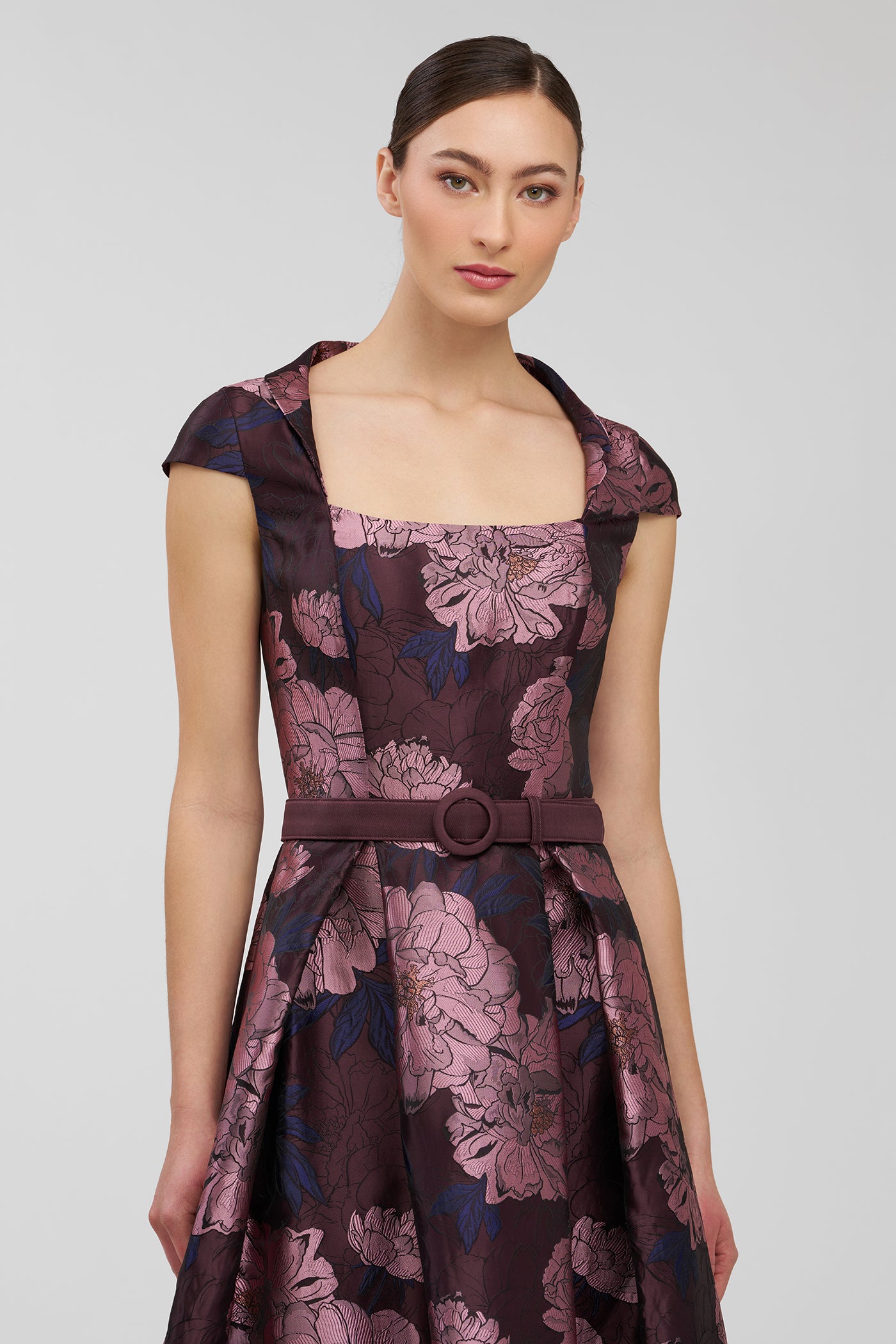 Woman wearing a floral patterned dress on a plain background