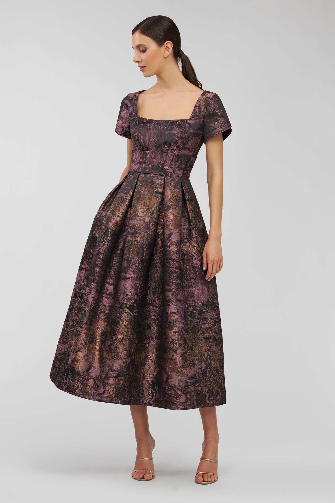 Woman wearing a patterned dress on a plain background