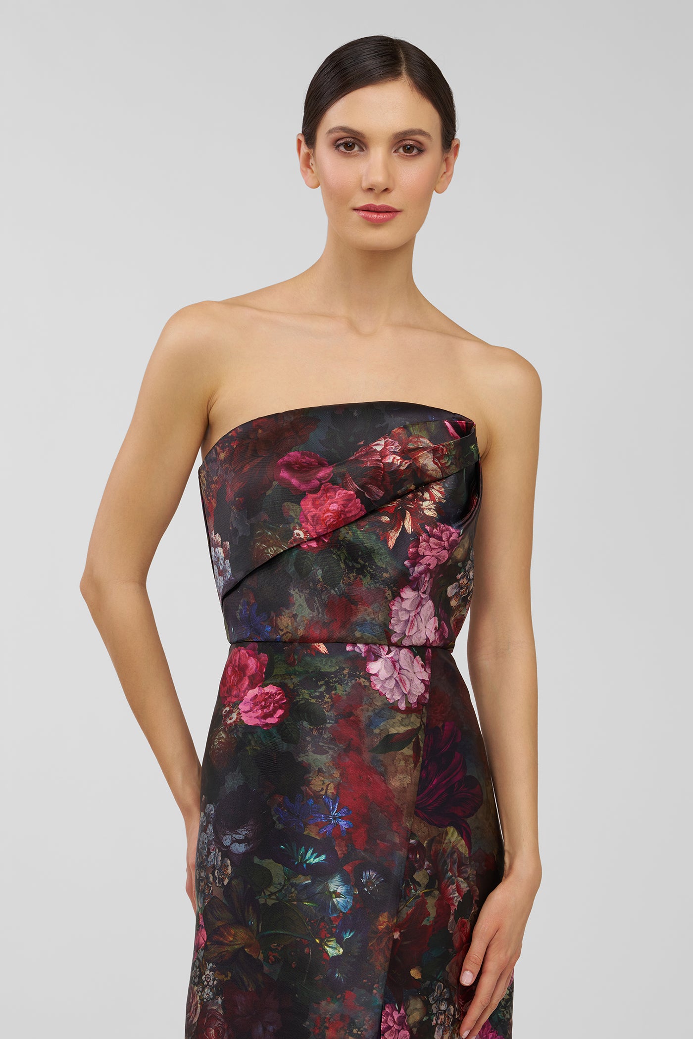 Woman wearing a strapless floral dress against a plain background
