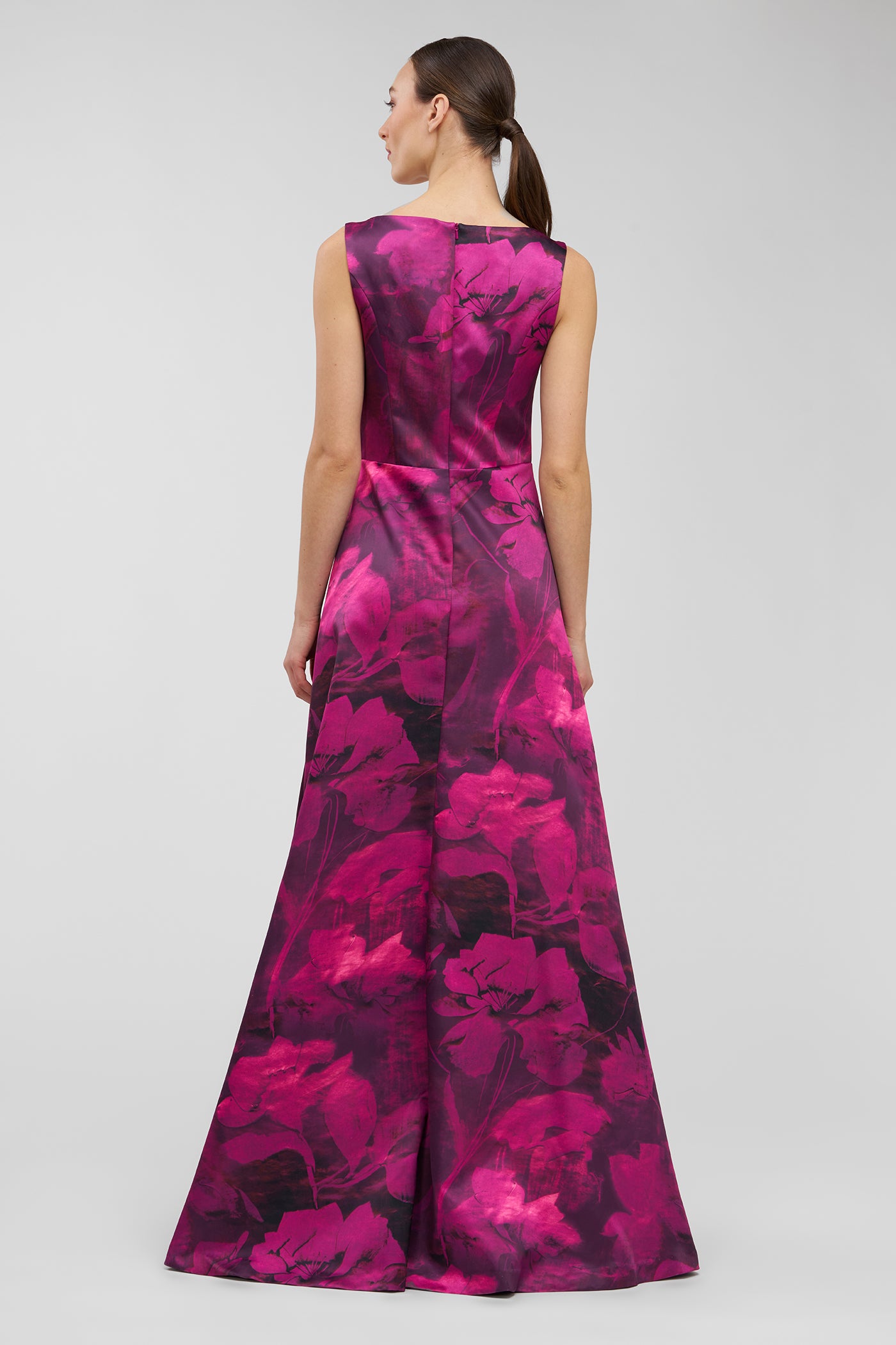 Woman wearing a vibrant pink and purple floral dress on a light gray background