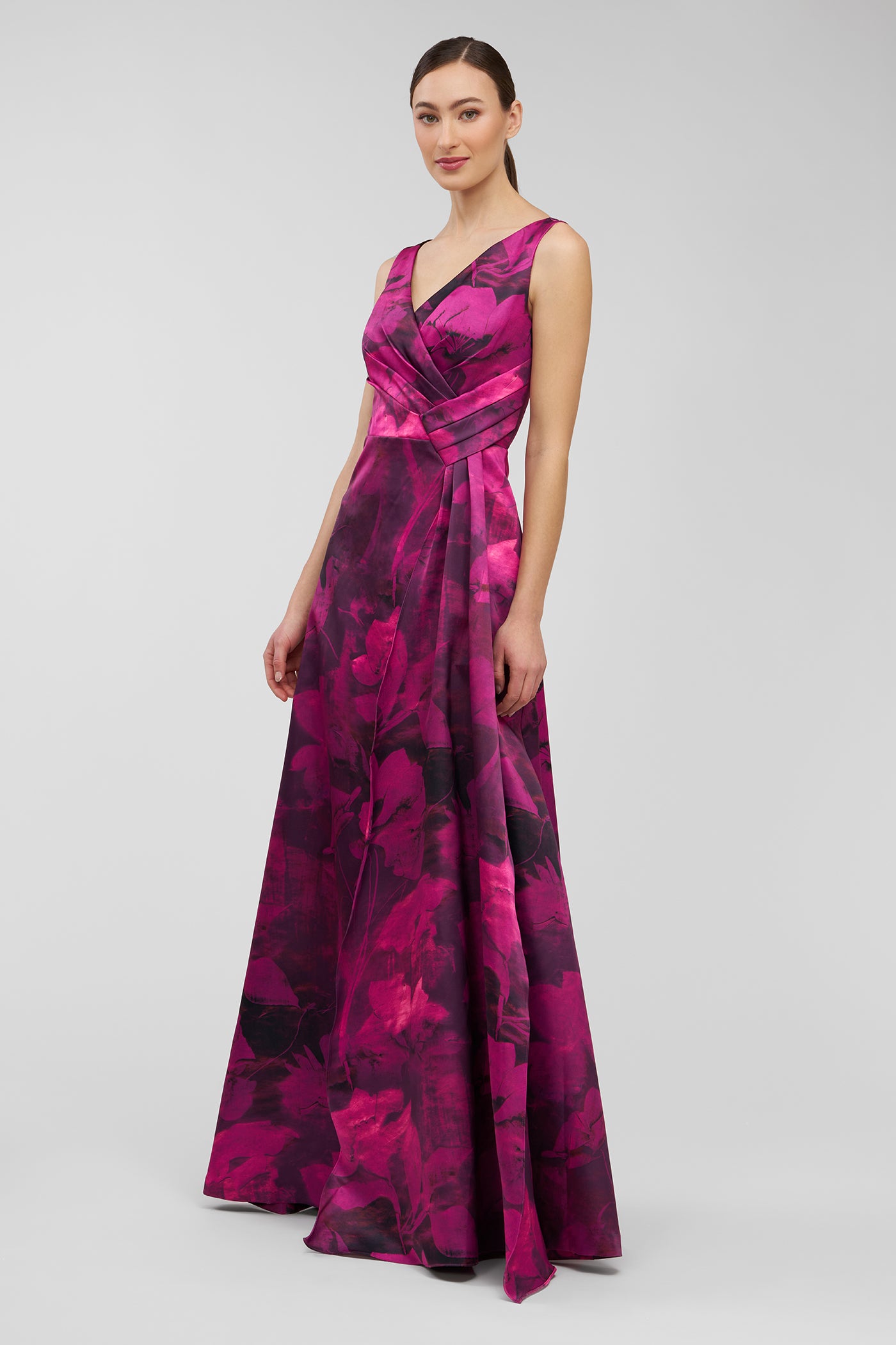 Woman wearing a vibrant pink and purple patterned gown on a light gray background