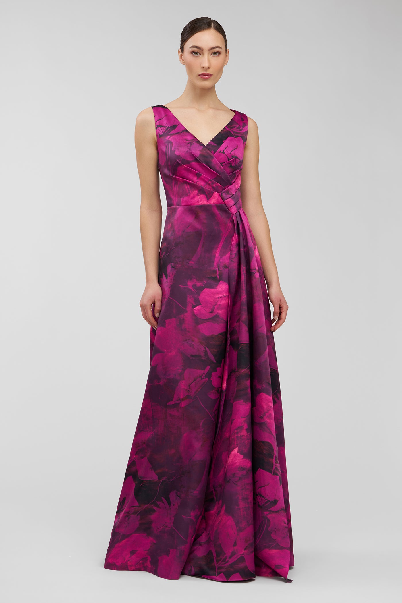 Woman wearing a vibrant pink and purple floral patterned gown on a light gray background