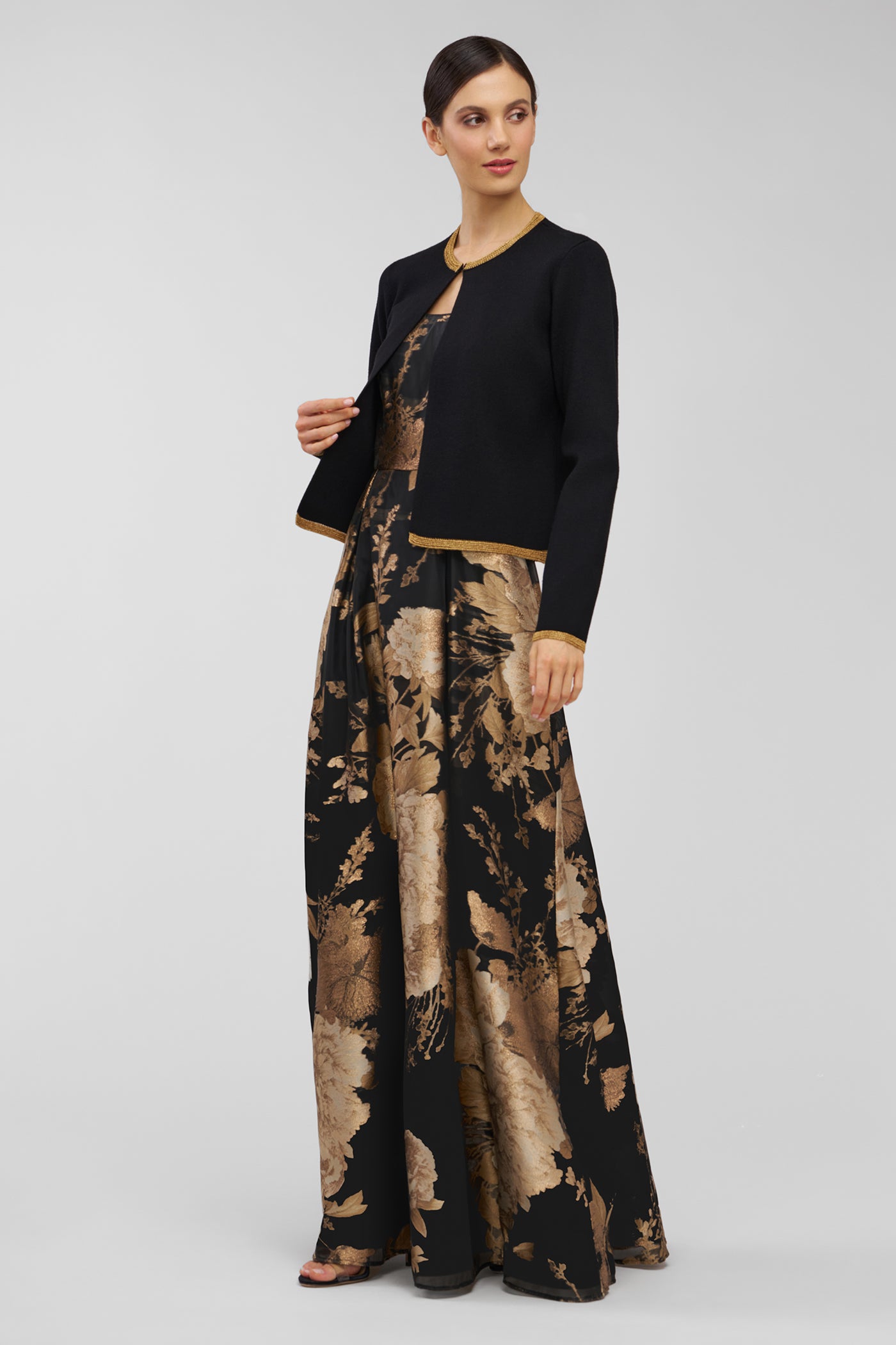 Woman wearing a black cardigan and patterned gown on a white background