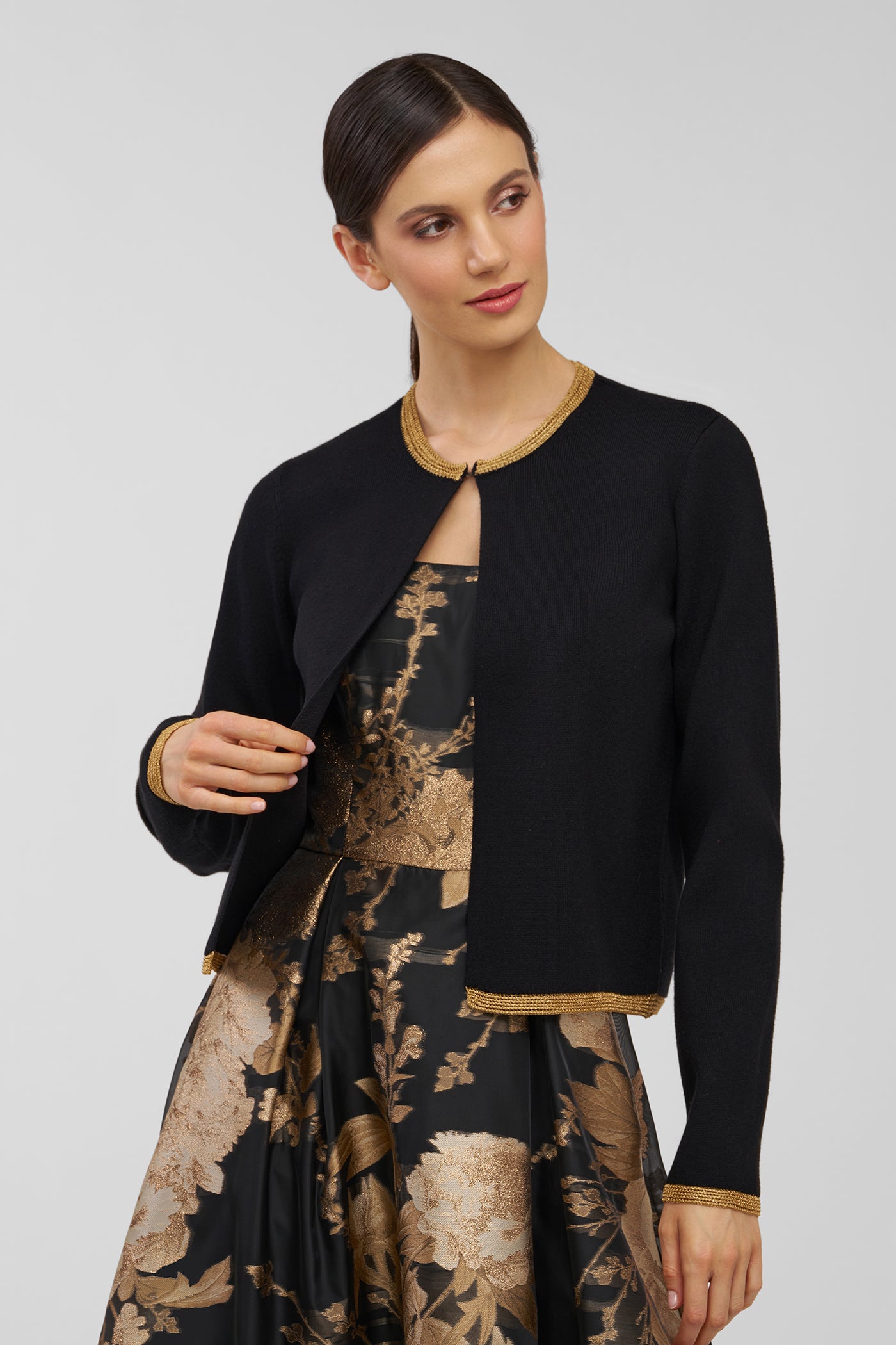 Woman wearing a black jacket over a floral dress on a plain background