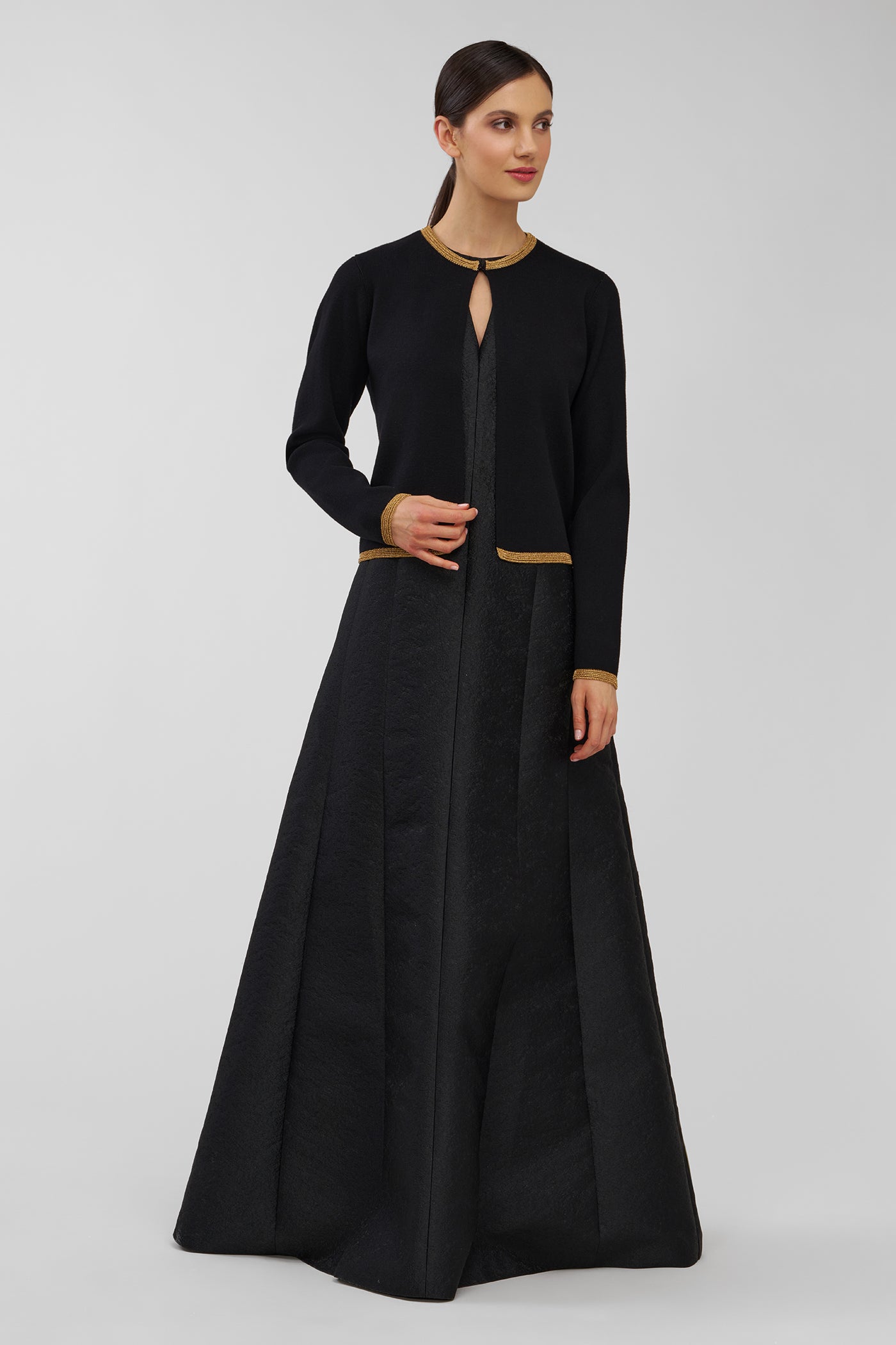 Woman wearing a black gown with a fitted cardigan on a white background