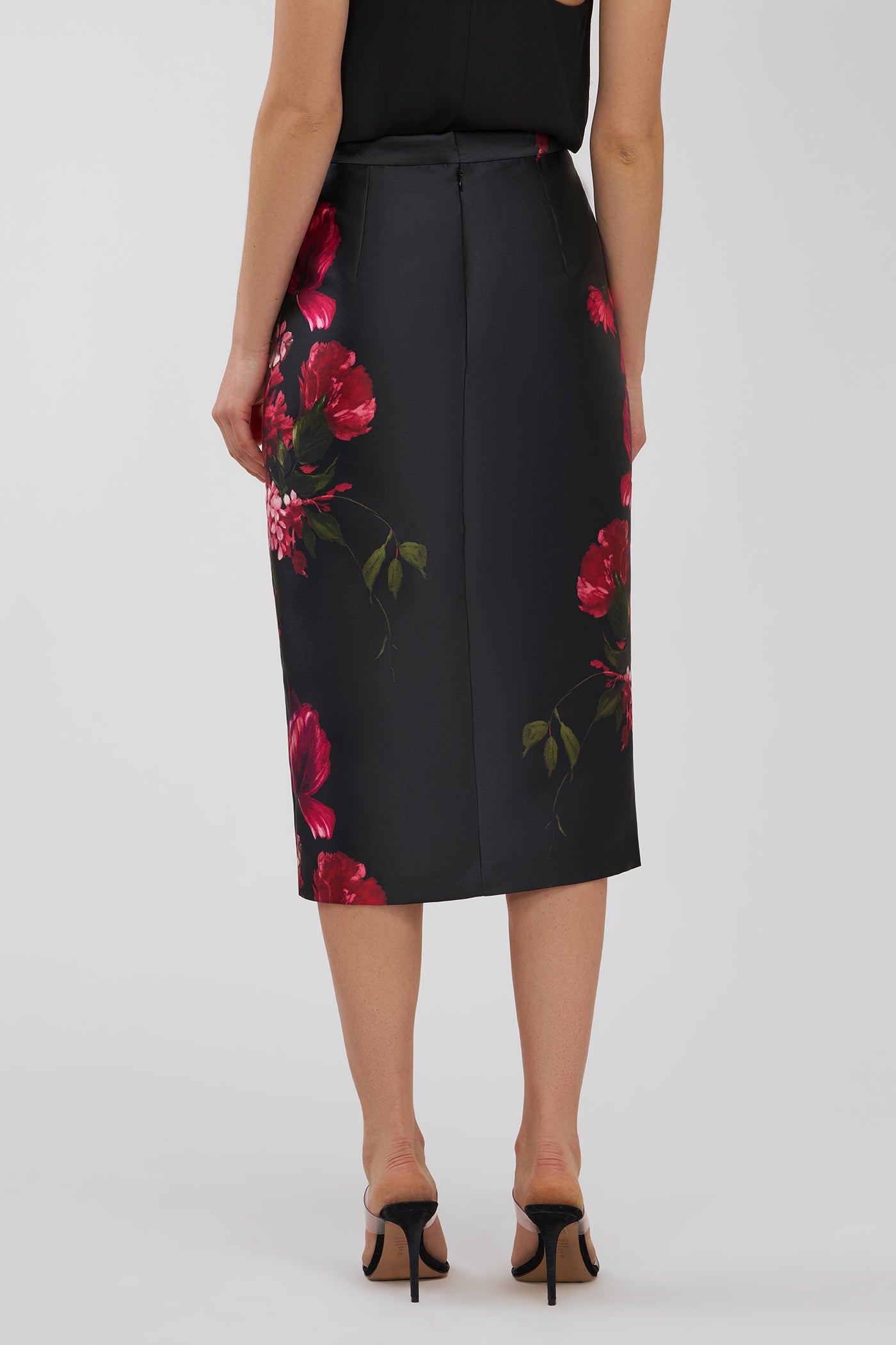 Black skirt with red floral pattern worn by a person on a white background