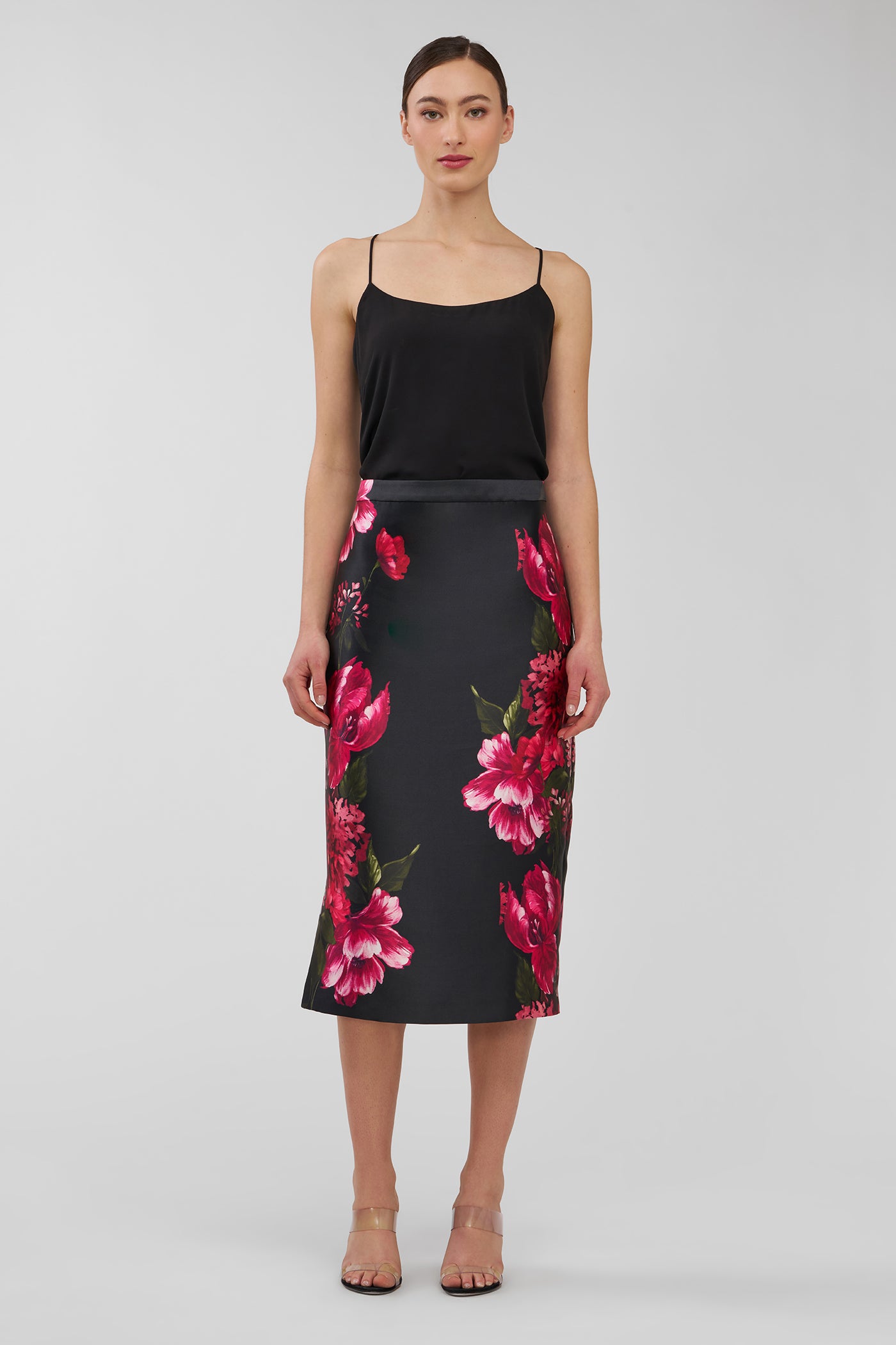 Woman wearing a black top and floral skirt on a white background