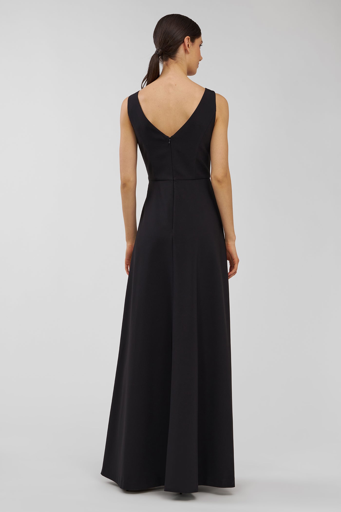 Black evening walk thru jumpsuit on a model against a plain background