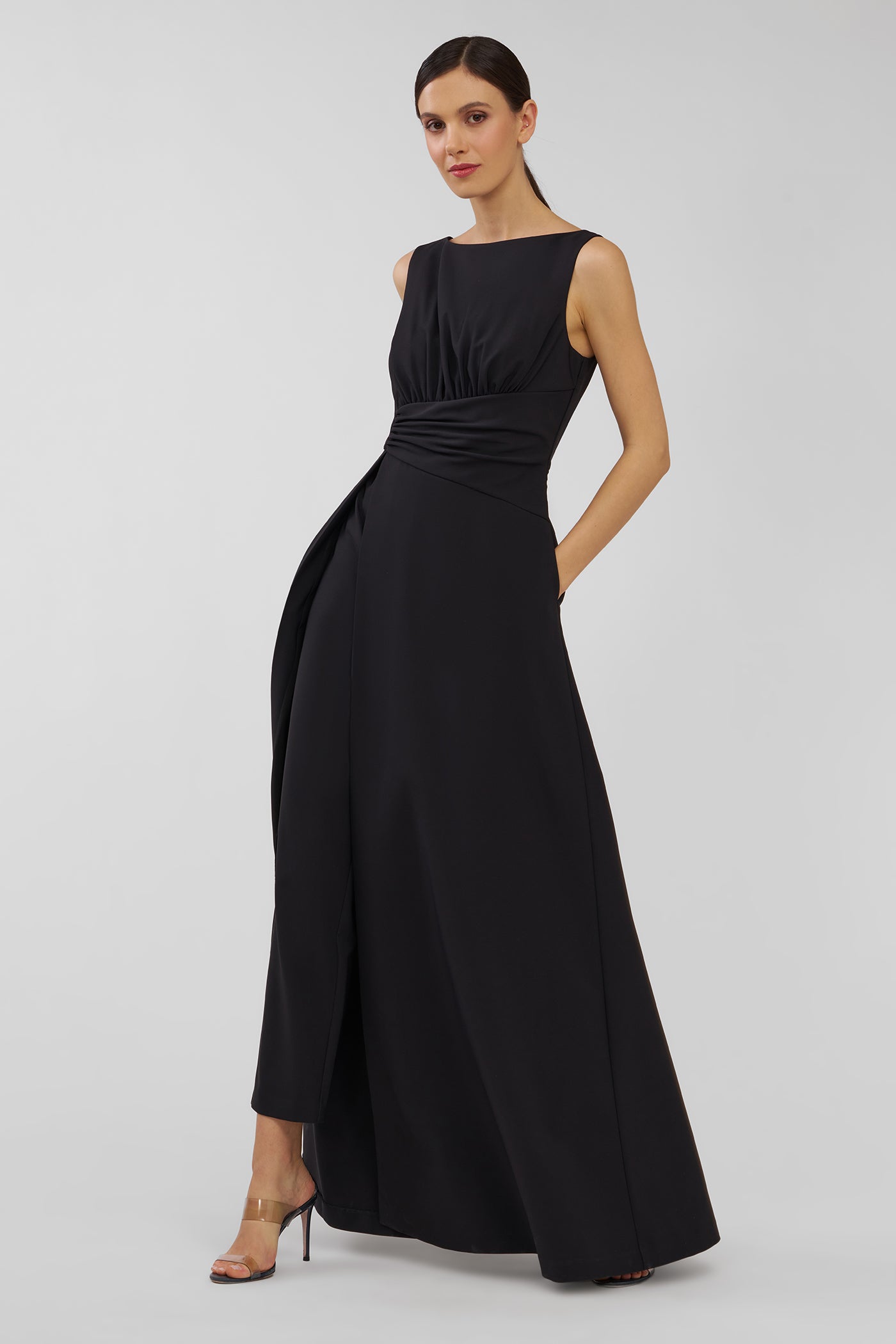 Woman wearing a black evening walk thru jumpsuit on a light gray background