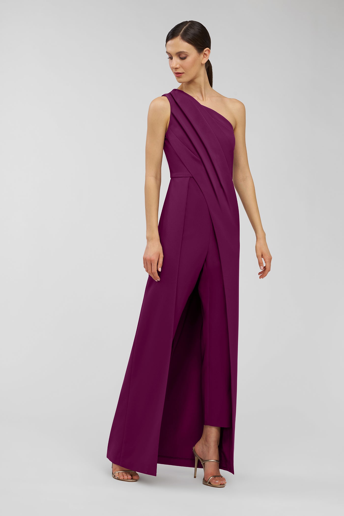 Woman wearing a purple one-shoulder jumpsuit on a white background